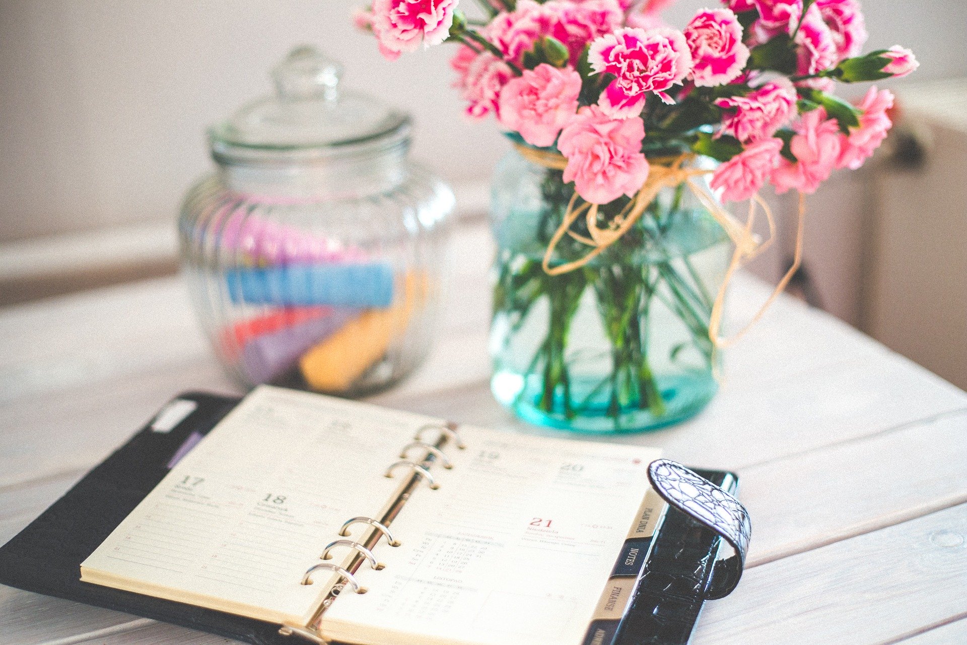 Pink Flowers Sitting on Desk with Daily Planner